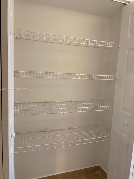 Bi-fold doors reveal a closet with white wire shelving and a tiled floor