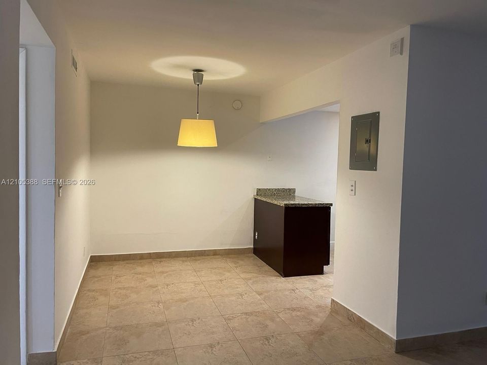 Tiled flooring, recessed ceiling light, pendant light fixture, built-in cabinetry with stone-finish countertop