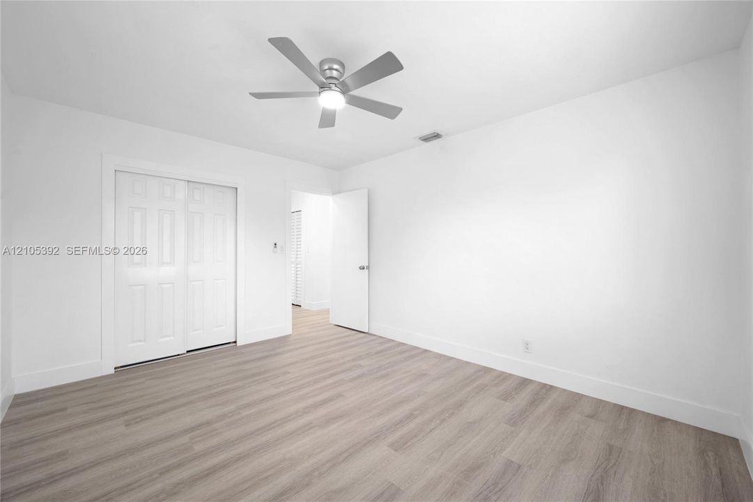 Light-toned wood-finish flooring, white walls, and a ceiling fan with integrated lighting