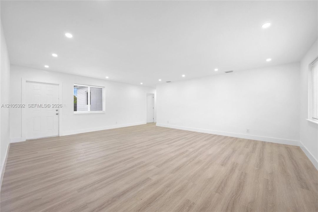 Spacious room featuring wood-finish flooring, recessed lighting, and white walls