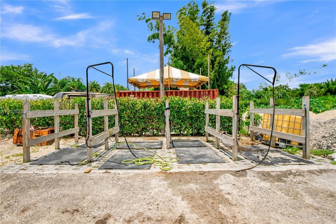 Outdoor wash stations featuring wooden post-and-rail fencing, concrete pad foundations, and overhead dual lighting
