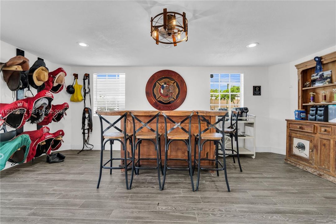 Custom wood-finish bar, wood-finish tile flooring, decorative ceiling-mounted light fixture, recessed lighting, and wall-mounted storage racks