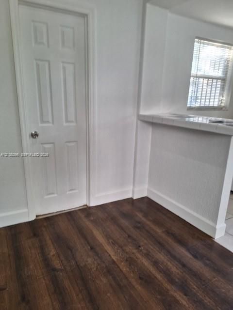 Wood-finish flooring with white baseboards and a paneled door