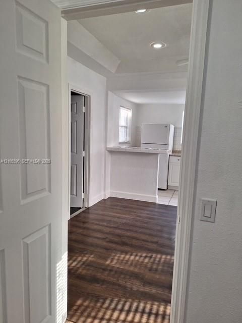 Wood-finish flooring, white paneled door, recessed lighting, and a kitchen pass-through with a countertop