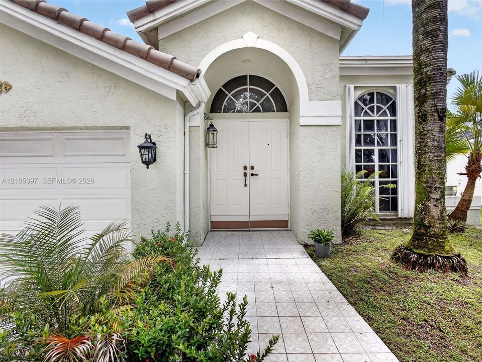 Stucco exterior featuring an arched entryway with a ramp, to  double doors.