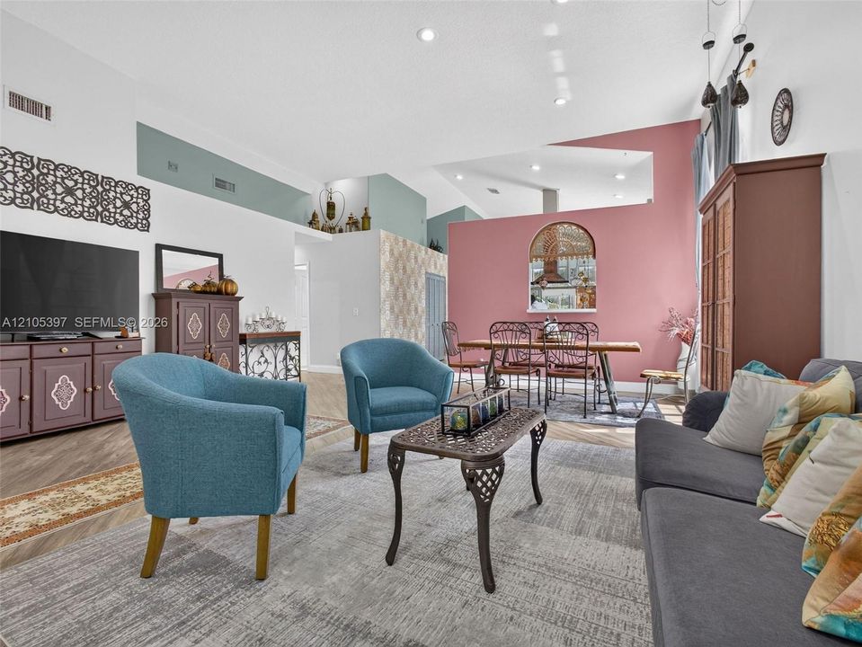 Open-concept floor plan featuring vaulted ceilings, recessed lighting, porcelain wood-finish flooring,
