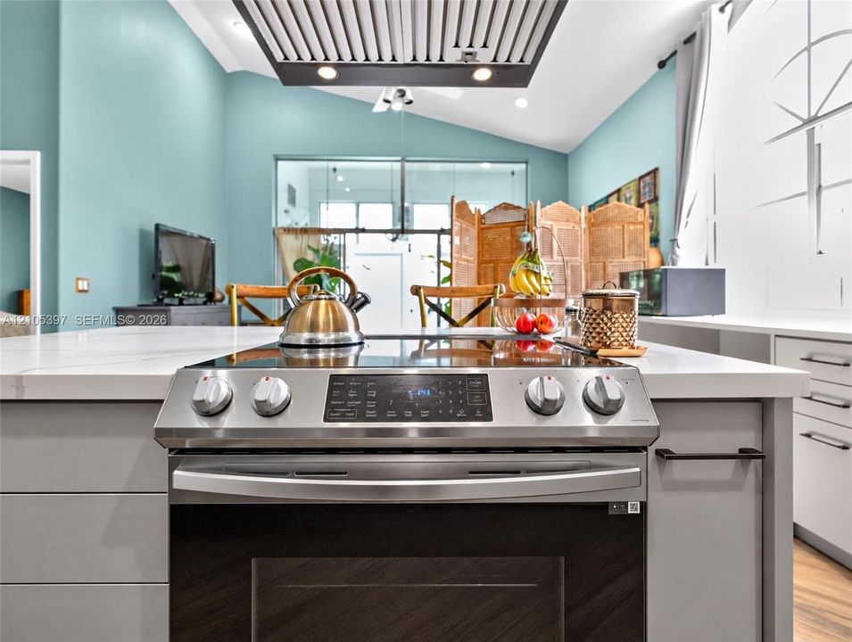 Kitchen island featuring a stone-surface countertop, stainless steel slide-in range, and flat-panel cabinetry