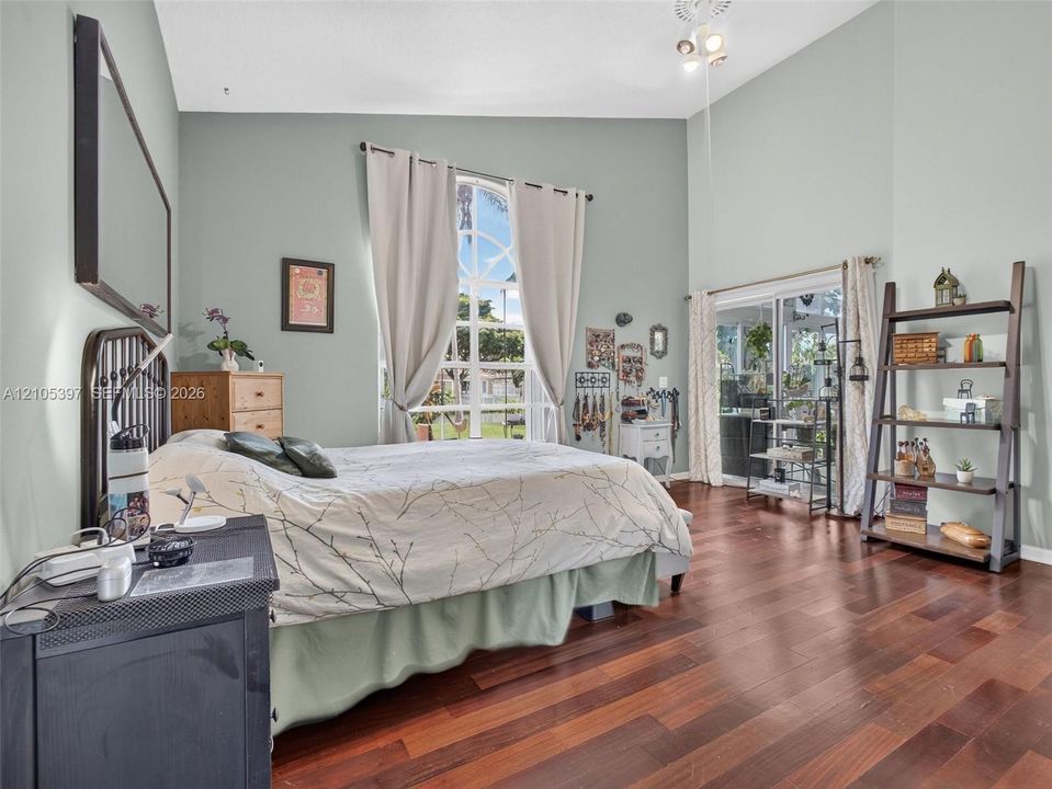 Vaulted ceilings, laminate flooring, an arched window, and sliding glass doors