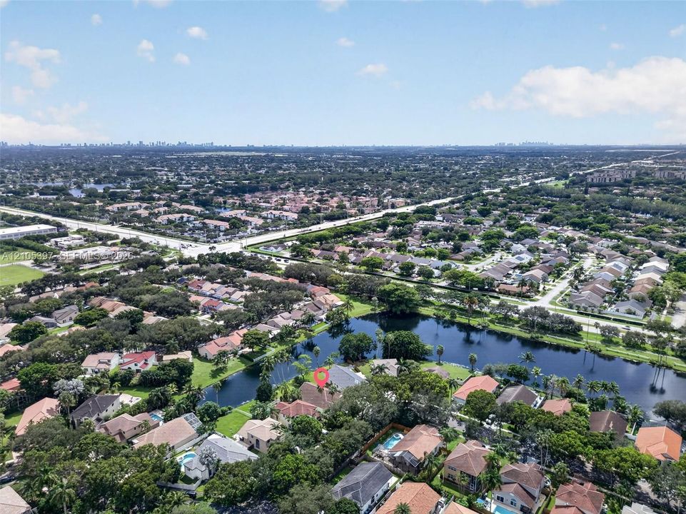 Aerial perspective featuring a waterfront lot, mature trees, and shingle-roof architecture