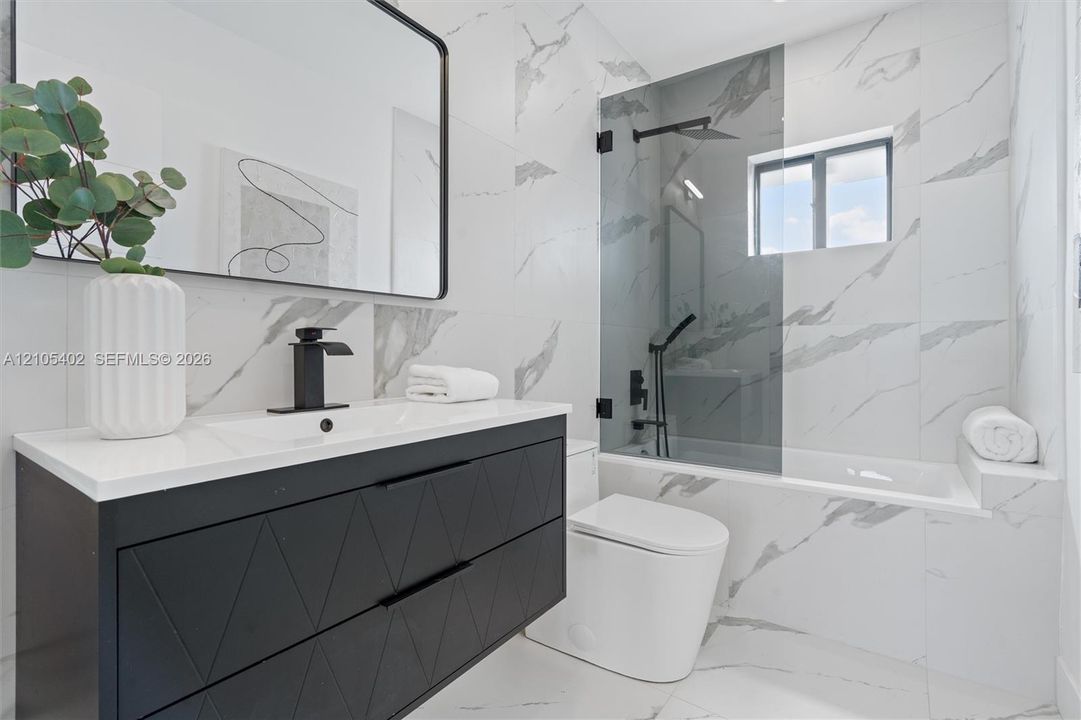 Modern floating vanity with a matte black geometric-patterned finish, white countertop, and black faucet