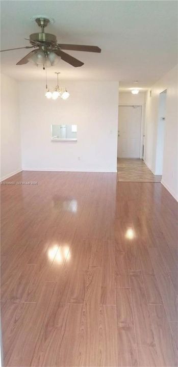 Wood-finish flooring throughout, ceiling fan with integrated lighting, recessed pass-through opening, and flush-mounted ceiling light fixture