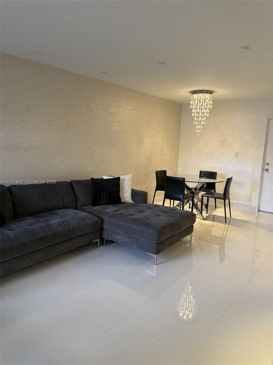 Recessed ceiling lights, textured accent wall, polished tile flooring, and a crystal chandelier