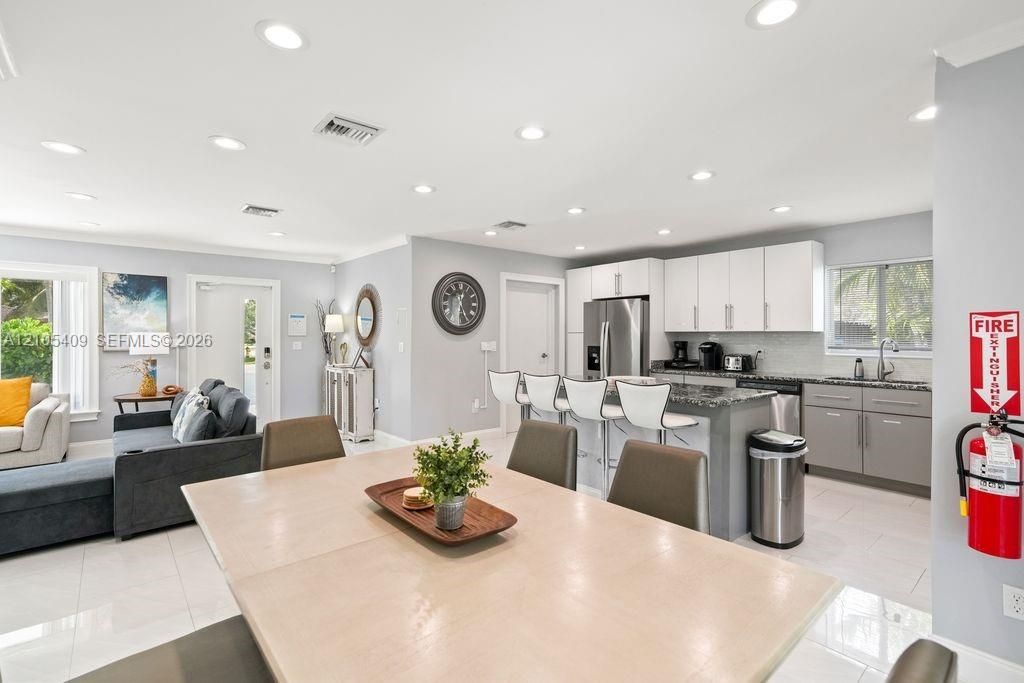 Open-concept living space with recessed lighting, tile flooring, and a kitchen featuring a center island with seating, stainless steel appliances, and two-tone cabinetry