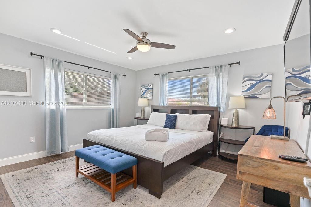 Recessed lighting, ceiling fan, wood-finish flooring, two windows, and light gray wall paint