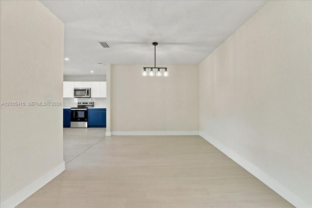 Open-concept interior featuring wood-finish flooring, a contemporary multi-light chandelier, and recessed lighting