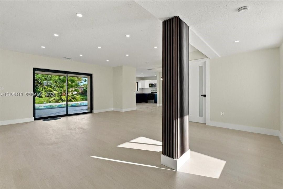 Open interior featuring wood-finish flooring, recessed lighting, a decorative fluted support column, and large sliding glass doors