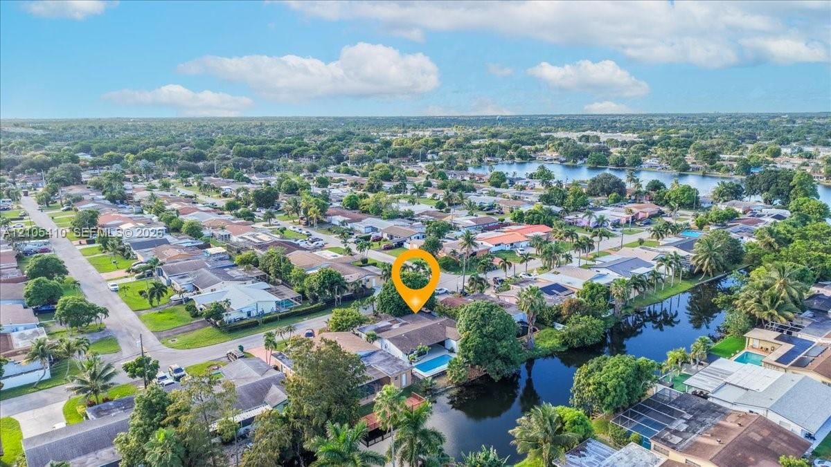 Aerial perspective featuring a waterfront property with an in-ground swimming pool and mature perimeter landscaping