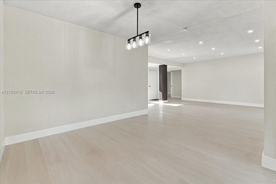 Open-concept interior featuring wood-finish flooring, recessed lighting, and a modern four-light linear pendant fixture