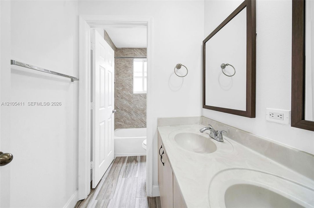 Double vanity with integrated sinks, framed mirrors, and wood-finish cabinetry