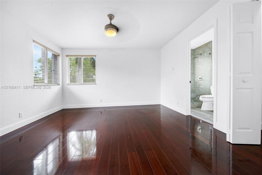 Dark wood-finish flooring, white walls, and a ceiling-mounted light fixture