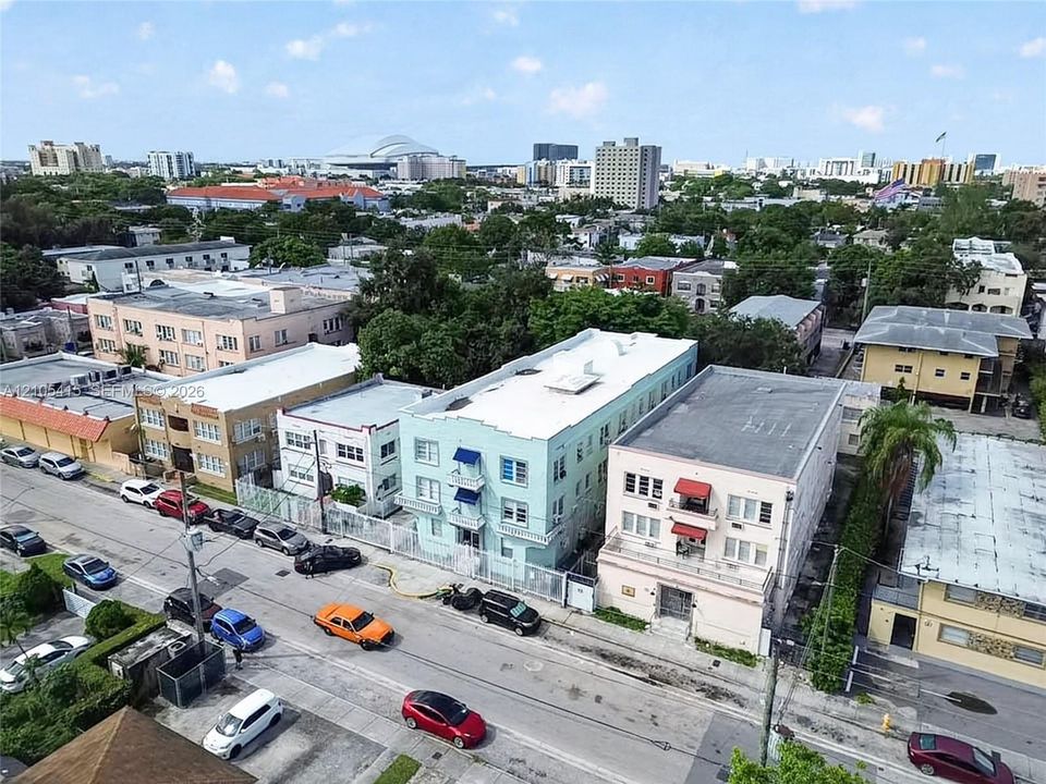 Multi-story urban residential building featuring a light-toned stucco exterior, flat roofline, and decorative awning accents