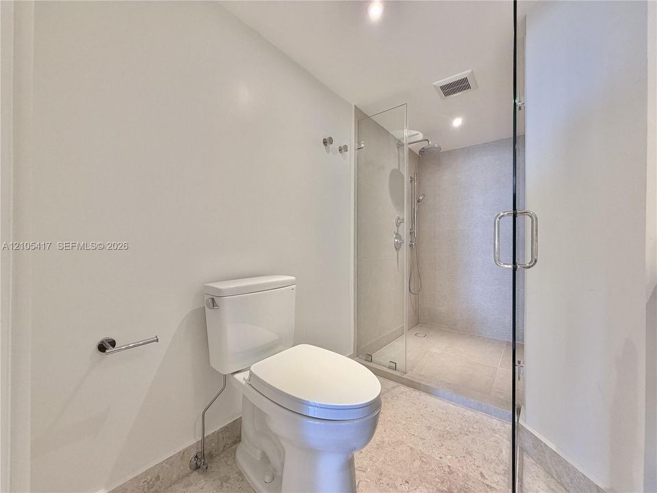 Full glass-enclosed shower with a rainfall showerhead, handheld shower fixture, and polished chrome hardware