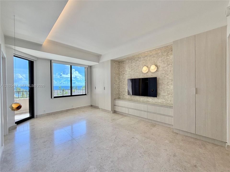 Integrated built-in cabinetry, recessed ceiling lighting, a wall-mounted media console, and a private balcony