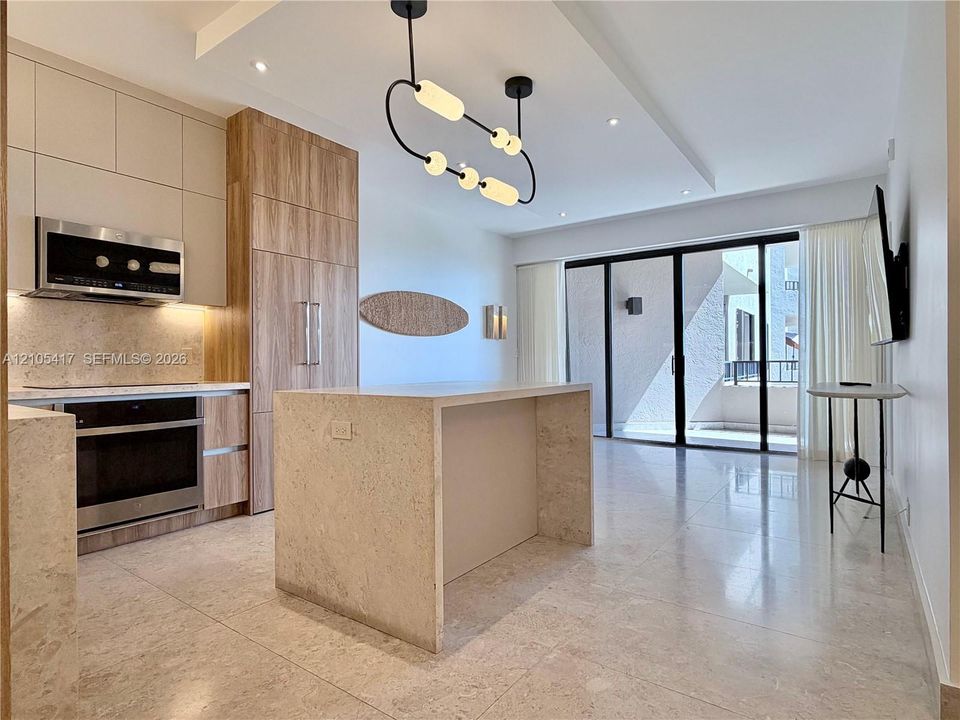 Modern kitchen featuring wood-finish cabinetry, stainless steel appliances, and a waterfall island with integrated seating