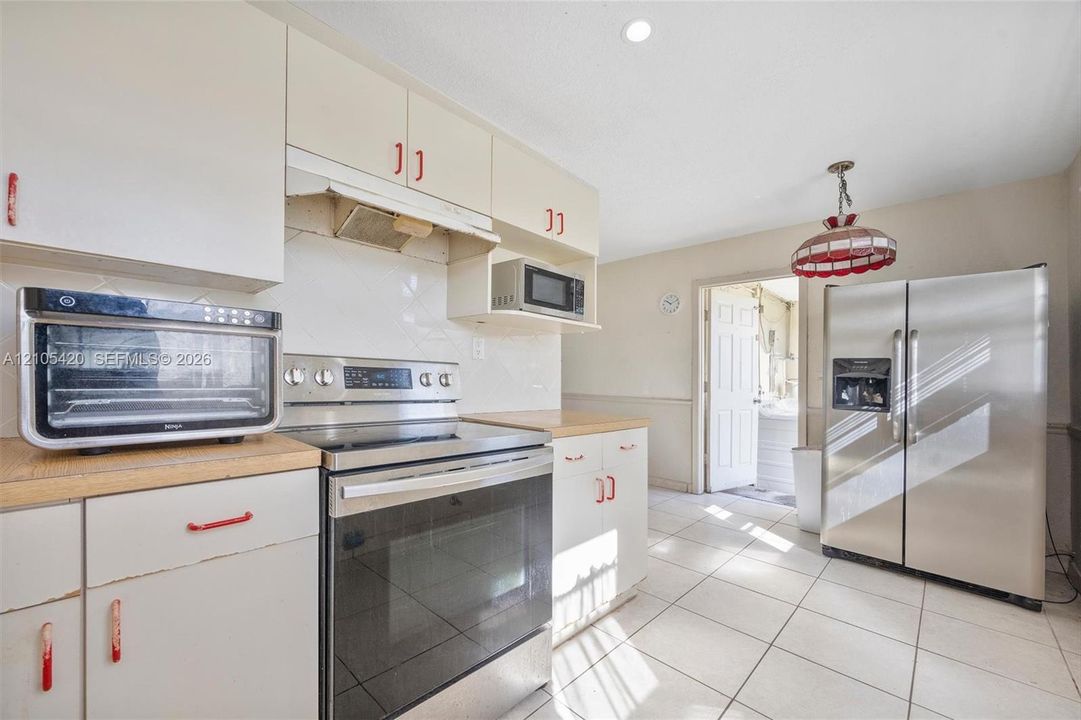 Kitchen featuring white cabinetry, light countertops, stainless steel appliances, and tile flooring
