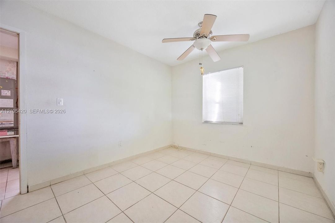 Square tile flooring, ceiling fan with integrated lighting, and a window with horizontal blinds