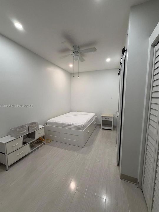 Light-toned wood-finish flooring, recessed lighting, ceiling fan, and louvered closet doors