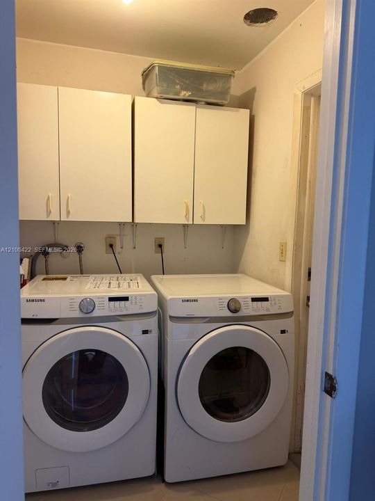 Dedicated laundry space featuring wall-mounted white cabinetry, recessed ceiling lighting, and dedicated water and electrical hookups