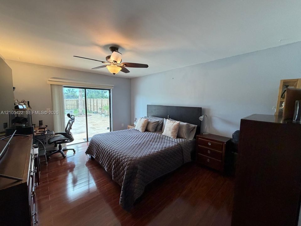 Room featuring wood-finish flooring, a ceiling fan with integrated lighting, and a sliding glass door providing external access