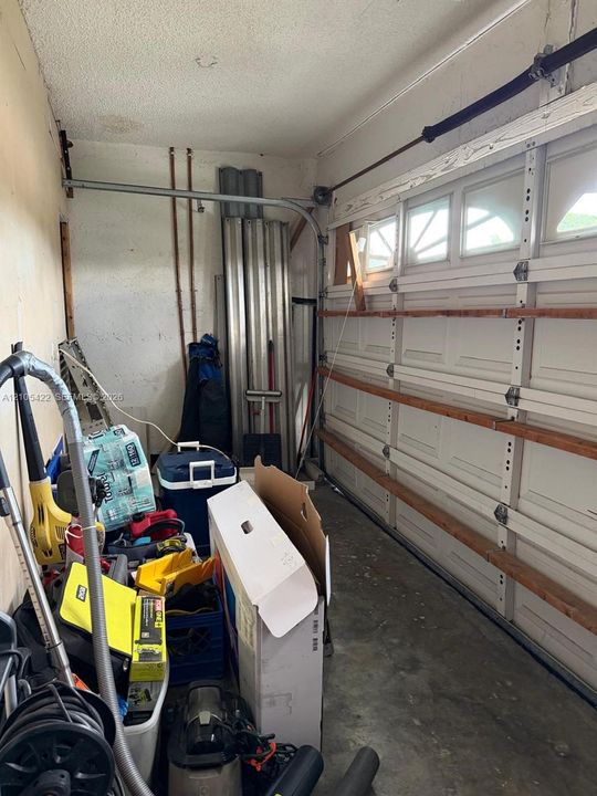 Garage interior featuring a sectional roll-up door with windows and exposed structural framing