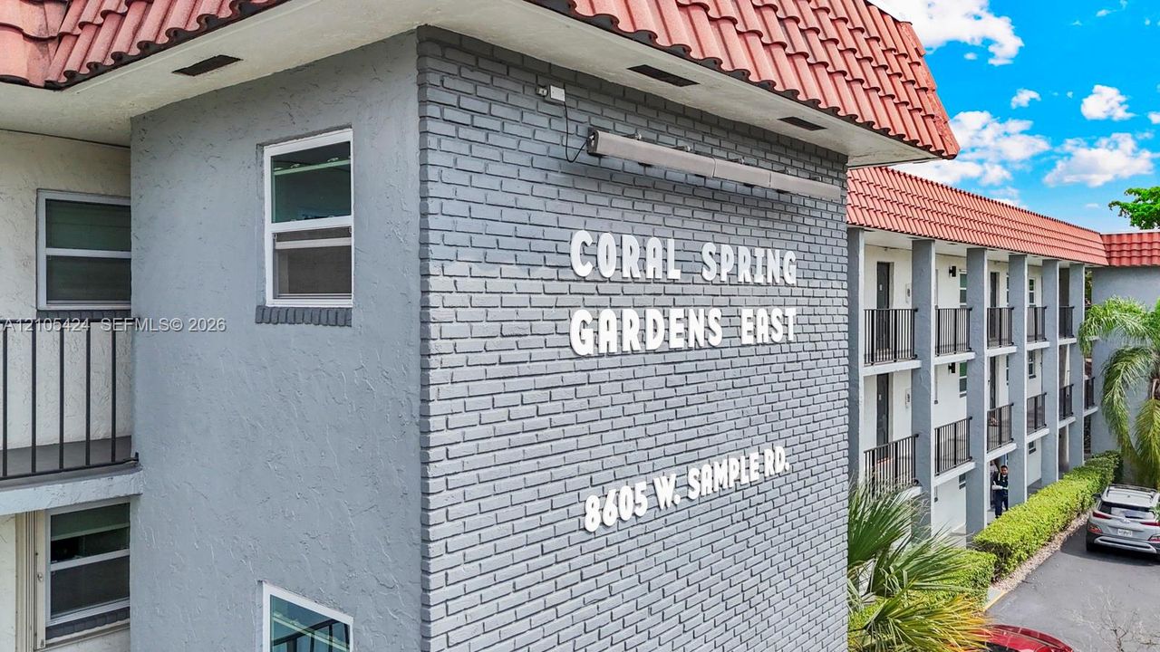 Coral Spring Gardens East building featuring a tiled roof and brick facade