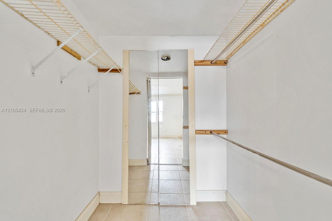 Reach-in closet featuring wire shelving, a metal hanging rod, and tile flooring