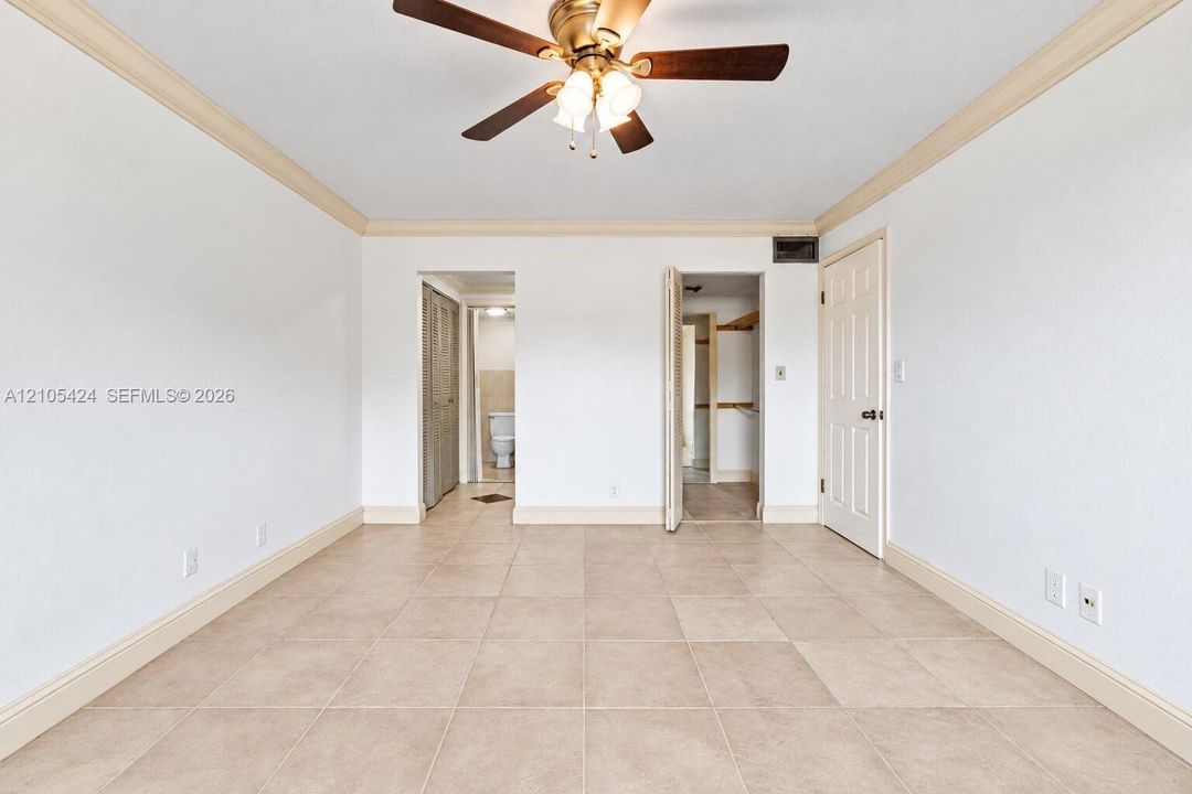 Recessed ceiling fan with wood-finish blades, crown molding, tile flooring, and white paneled doors