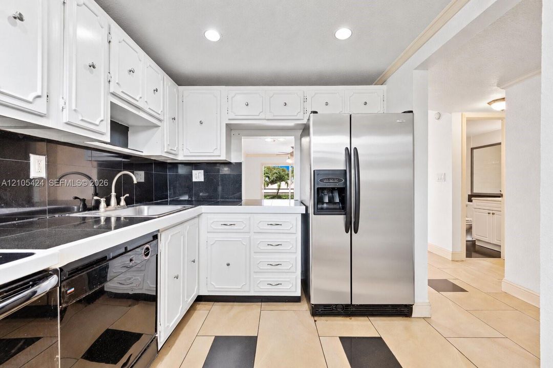 White cabinetry paired with dark countertops and a coordinating tile backsplash