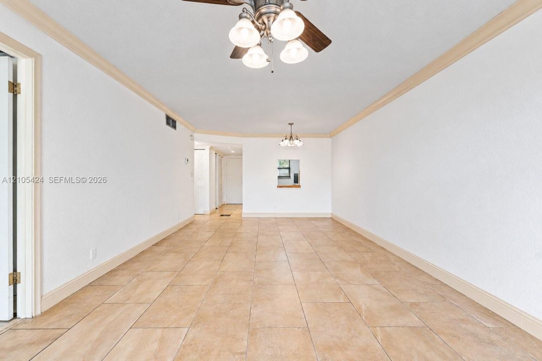 Spacious interior featuring neutral tile flooring, crown molding, and recessed lighting
