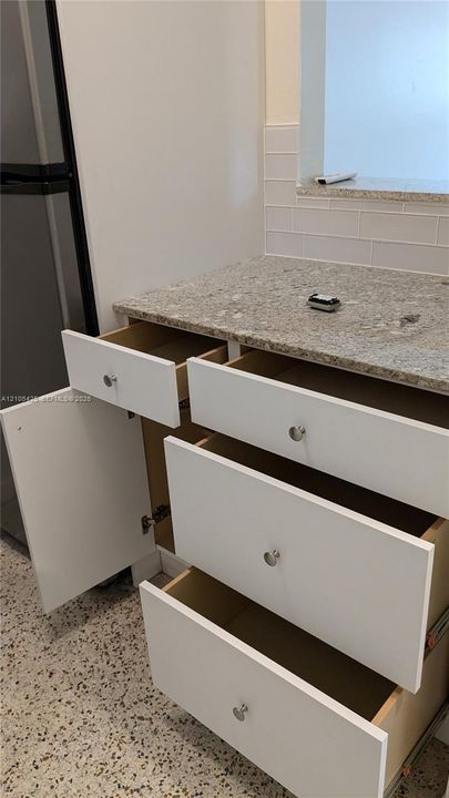 White cabinetry with brushed nickel hardware, speckled countertop, and white subway tile backsplash