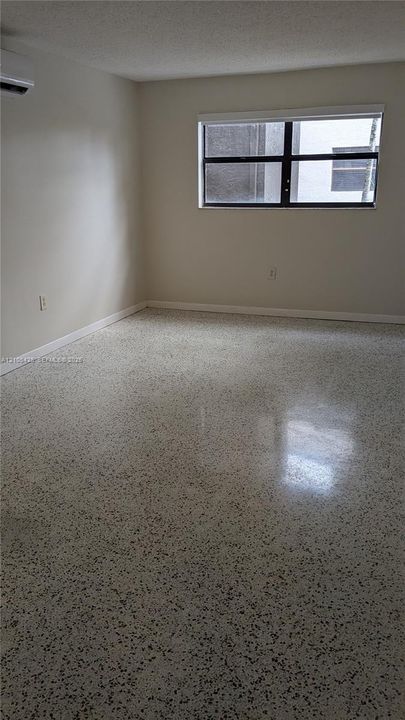 Polished terrazzo flooring, neutral wall tones, and a window with a roller shade