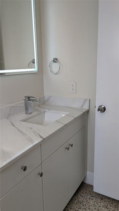 Vanity with a polished chrome faucet, an under-mount sink, and a light-colored countertop