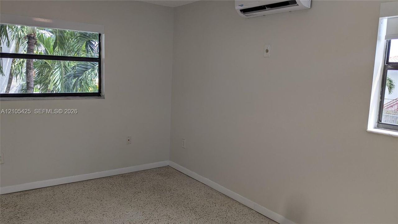 Textured flooring, light-toned walls, and multiple windows with exterior scenery