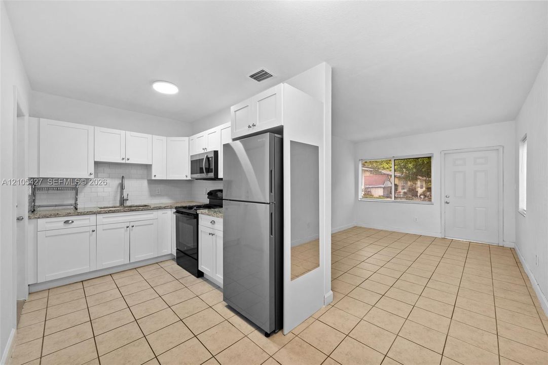 White kitchen cabinetry with granite countertops, stainless steel appliances, and a subway tile backsplash
