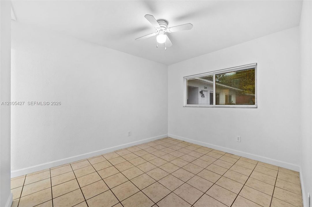 Neutral tile flooring, white ceiling fan with integrated lighting, and a window with horizontal blinds