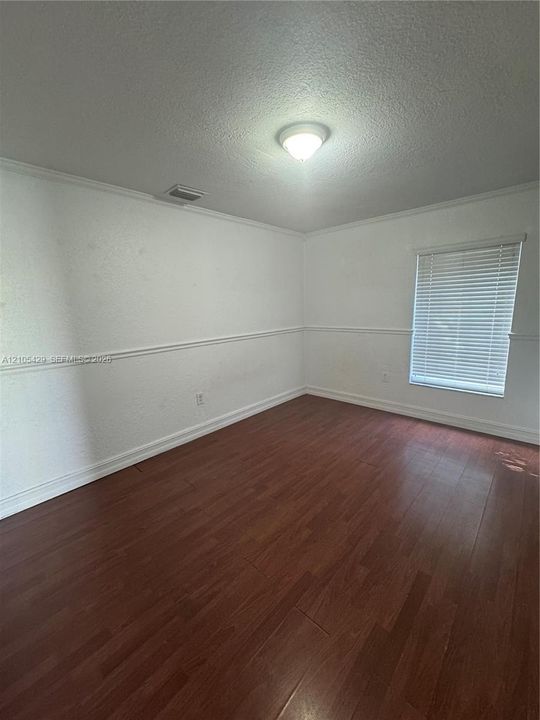 Wood-finish flooring, white walls, and a window with horizontal blinds