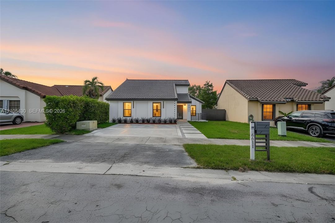 Single-story residence featuring a tile roof, light-toned exterior finish, paver-accented driveway, and manicured landscaping