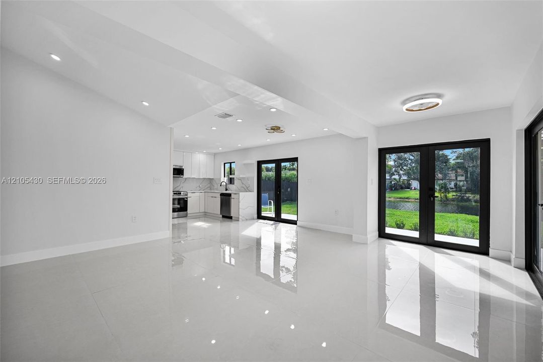 Open-concept interior featuring large-format polished tile flooring, recessed lighting, and kitchen with quartz countertops