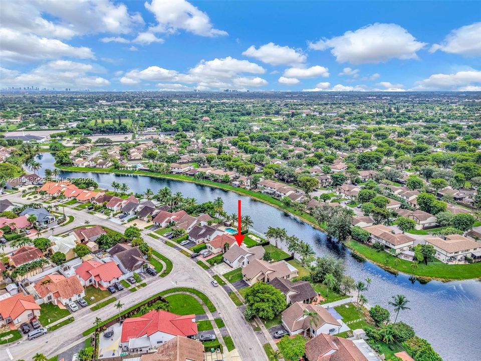 Aerial perspective of a waterfront property featuring a canal-front lot, a private backyard swimming pool, and a tile roof