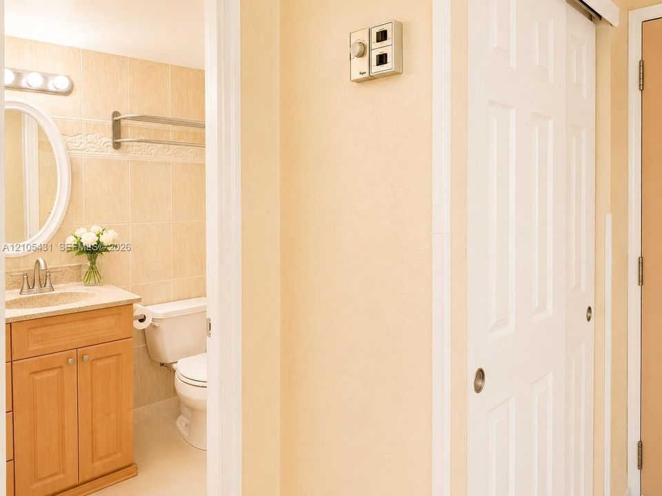 Bathroom with a wood-finish vanity, light-toned countertop, oval mirror, and tile-surround wall